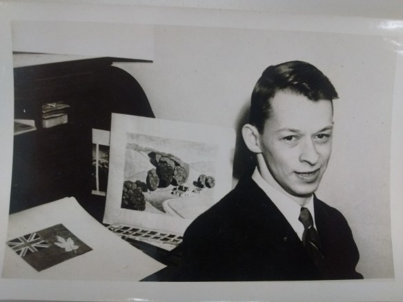 A black-and-white photograph of a man looking towards the camera with a flag design in the background.