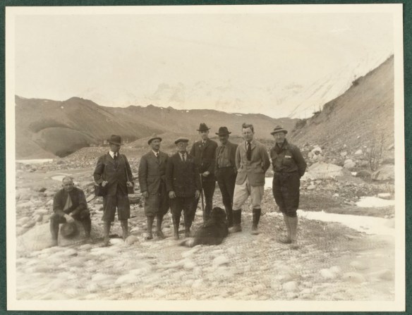 A sepia coloured photograph of a group of men with Mount Logan in the background.