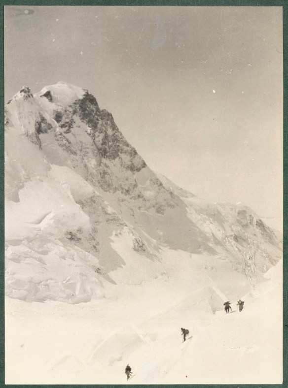 A photograph of Mount Logan with four climbers in the foreground.