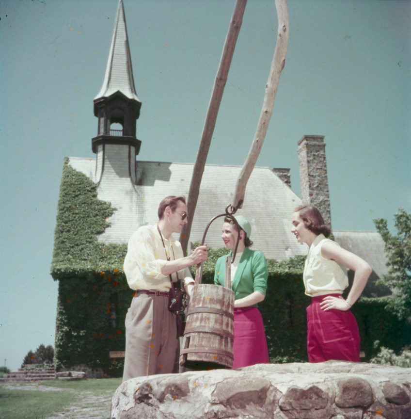 Three tourists standing beside Evangeline’s well, in front of the Acadian Memorial Church.