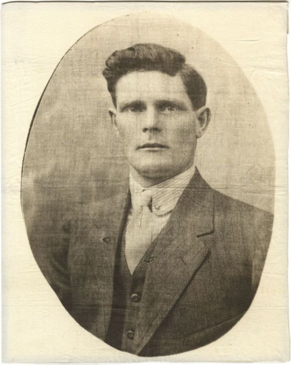 Photographic portrait printed on linen of a young man shown from the chest up, wearing a button-down shirt, tie, vest and suit jacket in an oval frame.