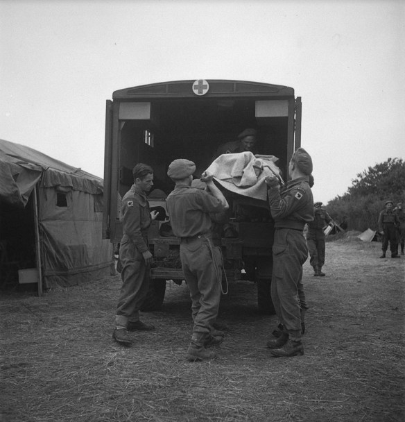Soldiers load a wounded soldier on a stretcher into a military ambulance.