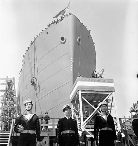 Bow of ship with naval officers at attention.