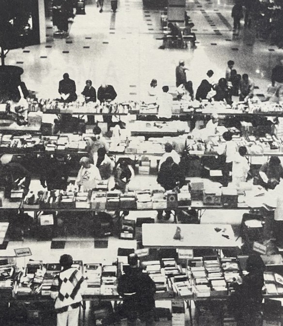 Photograph of people going through books placed on tables in a mall.